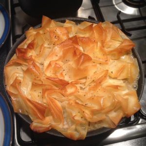 Photo of the delicious one-pan chicken pie with filo pastry on top of a gas hob