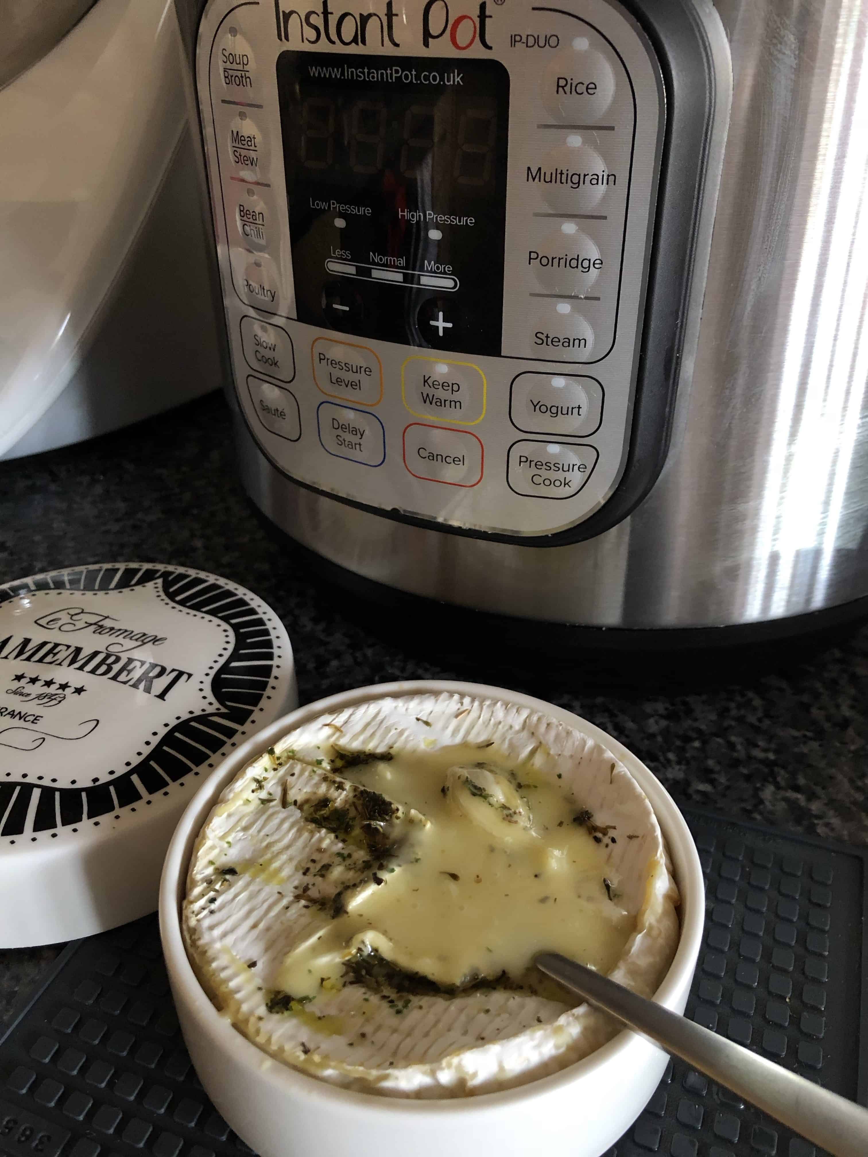 Instant Pot Baked Camembert pressure cooked in a ceramic blue and white Camembert Baker with herbs and garlic with the Instant Pot DUO in the background