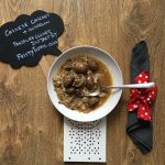 Helen's Instant Pot Chinese Chicken and Mushroom served on a deep white plate with a dark grey napkin on the right, with a red and white ribbon. There's also a chalkboard with the name of the recipe in the photo