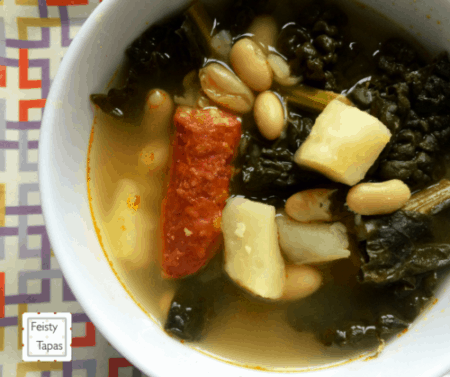 Instant Pot Soup with Greens, Beans, Potatoes Chorizo served on a deep white soup plate. This soup is based on the traditional Spanish Caldo Gallego, a delicious wholesome soup
