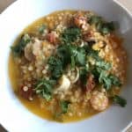 Delicious and super quick Instant Pot Giant Cous Cous with seafood served in a deep white dish against a light wooden table