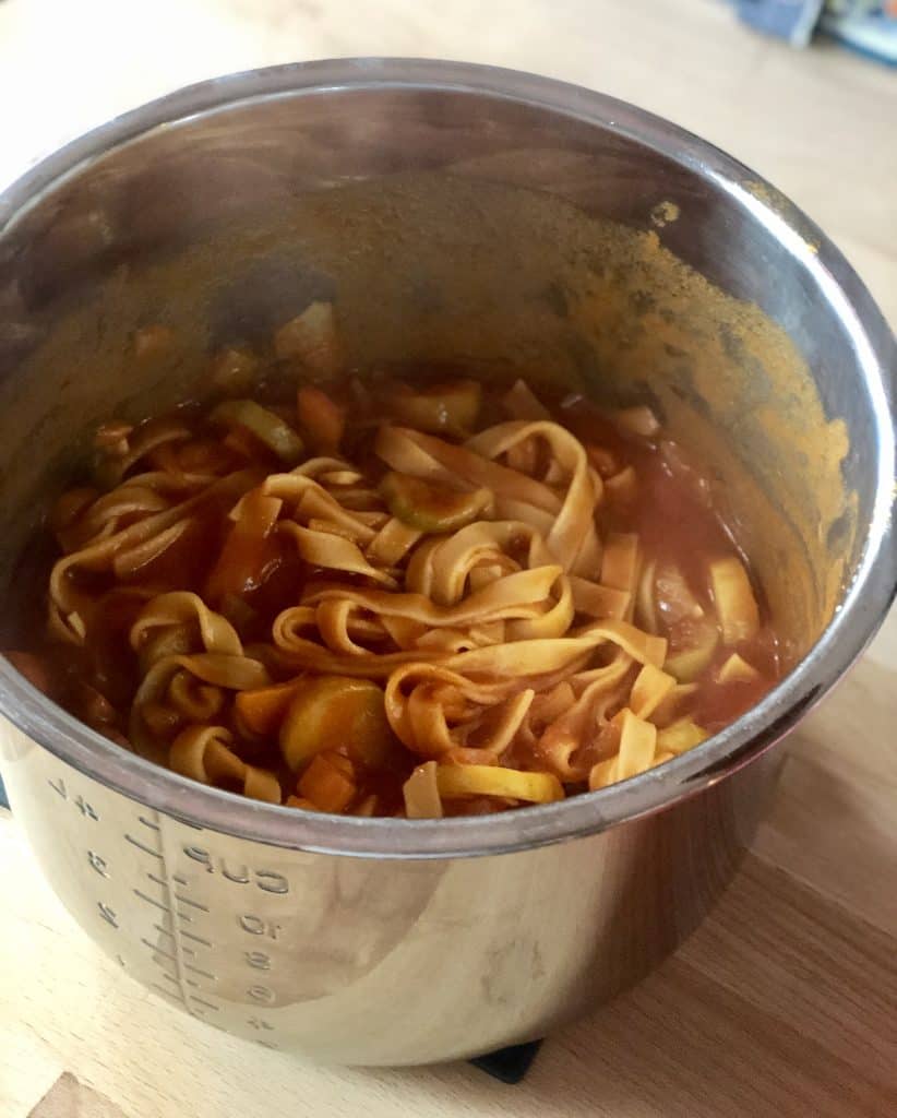 Delicious Instant Pot Chorizo Pasta in the stainless steel inner pot. Lovely tagliatelle. Shown on a wooden table