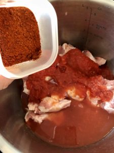 Paprikas and salt being added to Easy Instant Pot BBQ Pulled Pork recipe by Feisty Tapas