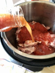 Water from rinsing passata jar being poured into Easy Instant Pot BBQ Pulled Pork recipe by Feisty Tapas