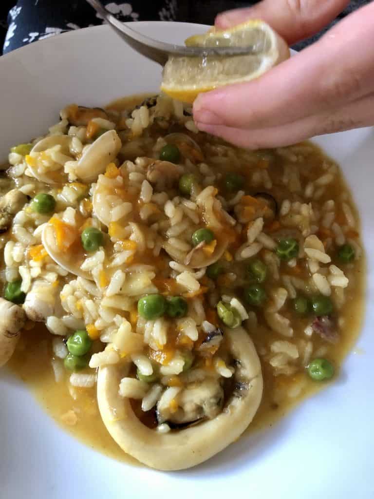 Drizzling lemon over Instant Pot Seafood rice 