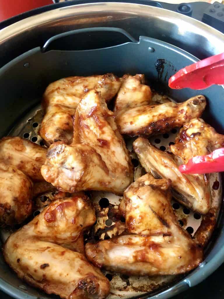 Instant Pot Duo Crisp Chicken wings being turned with red tongs