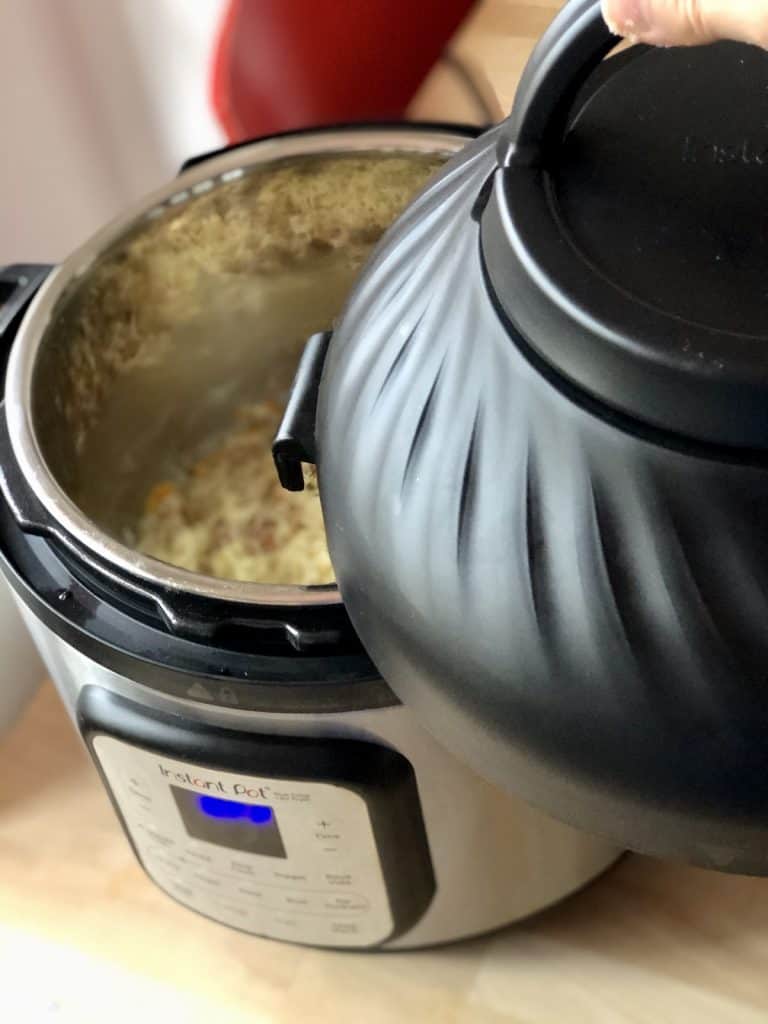 Instant Pot Duo Crisp lid with gammon rice in the bakground - putting lid on