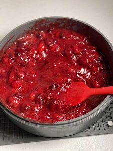 Cranberry sauce seen in a grey silicone cake pan after stirring and squeezing