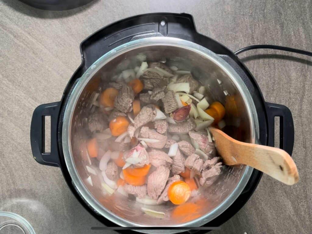 Diced beef and vegetables seen from above inside the stainless steel inner pot of the Instant Pot Duo