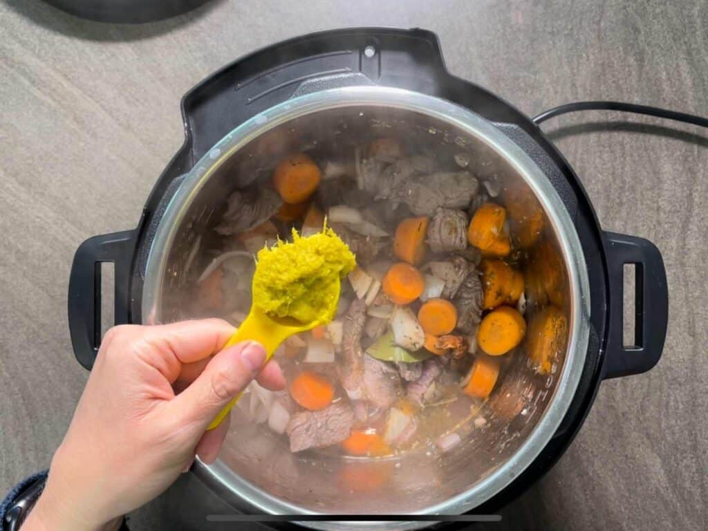 Vegetable stock paste seen from above about to be added to the beef stew