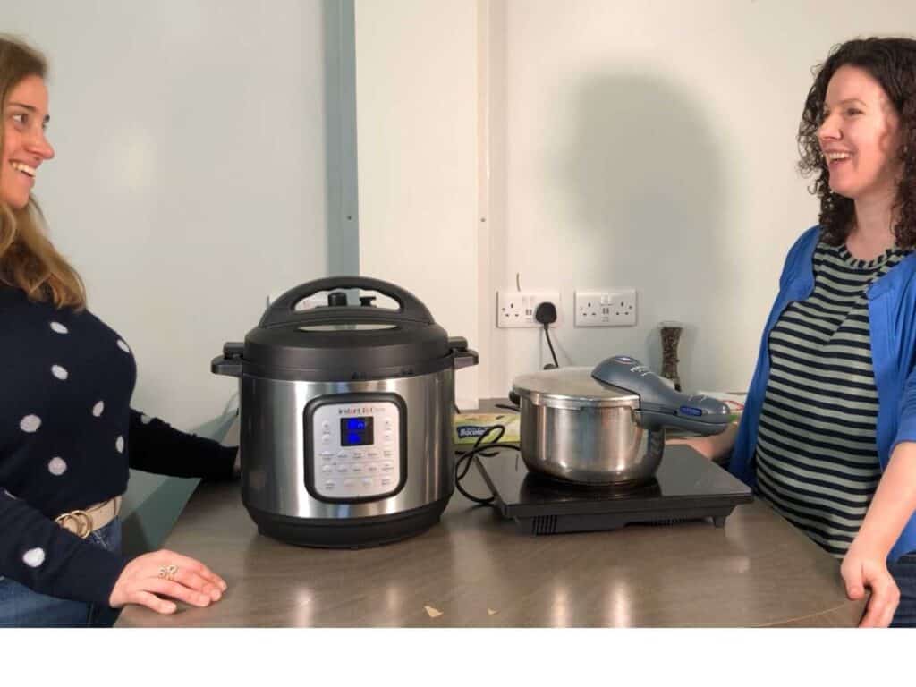 Maria Bravo from Feisty Tapas filming with Catherine Phipps at The Kitchen Gadget Hub. Maria is on the left, wearing a dark jumper with polka dots, next to an Instant Pot Duo Crisp and Catherine is on the right wearing a stripy top and a blue cardigan. They're both smiling and looking at each other