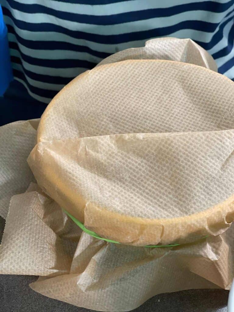 Greaseproof paper with a pleat being held in place to a pudding basin with a elastic band