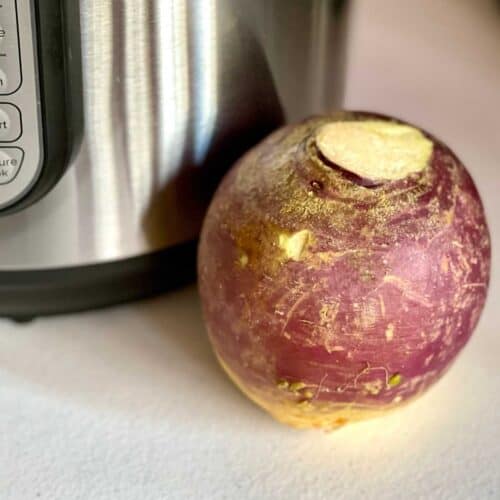 Whole Swede or Rutabaga (uncooked) on a white textured surface, in front of an Instant Pot Duo