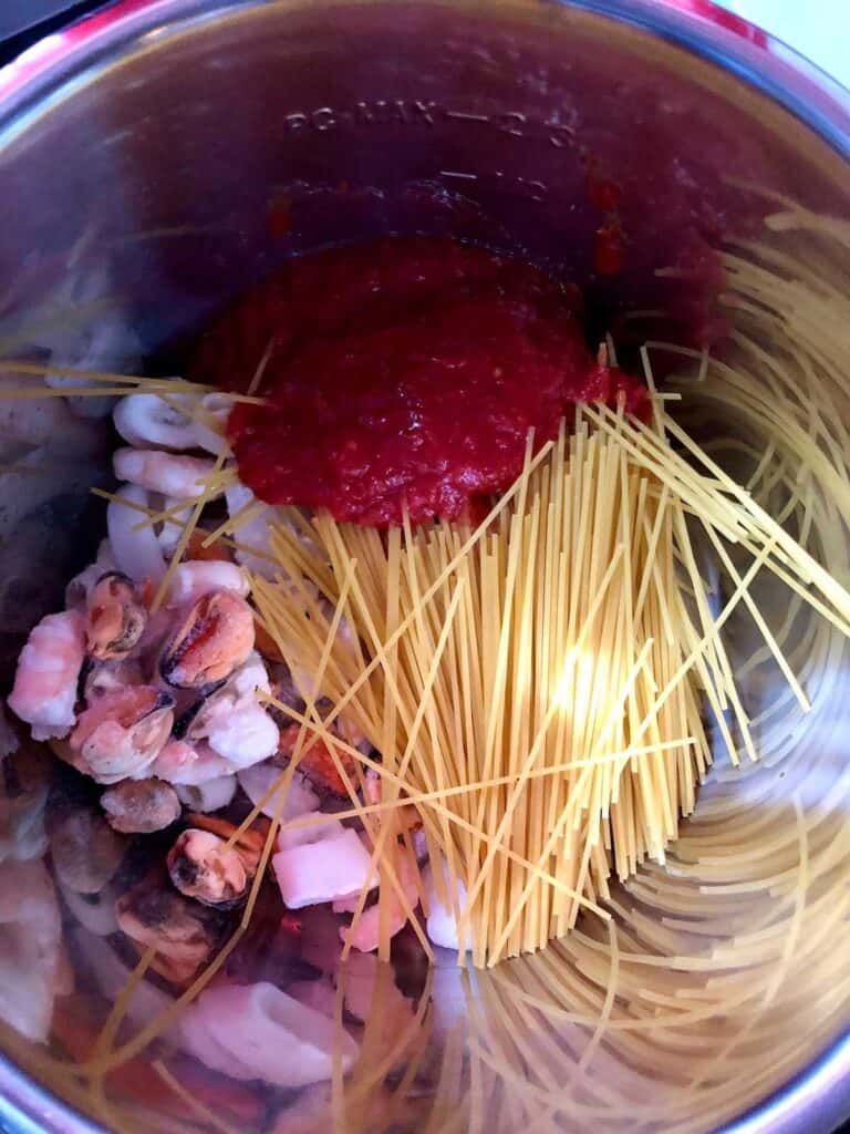 Ingredients for mixed seafood spaghetti recipe before pressure cooking, seen from above in the Instant Pot's stainless steel inner pot