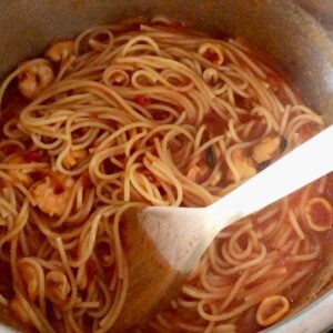 Pressure Cooker Mixed Seafood Spaghetti seen from above with a wooden spoon for stirring it