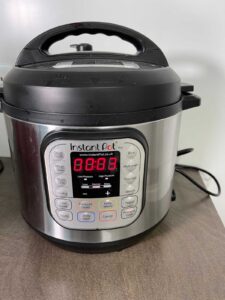 Instant Pot Duo Crisp multicooker with 00.03 on the display, on a taupe brown kitchen counter, meaning it has been programmed to pressure cook 3 minutes