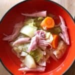 Mouthwatering photo of an orange bowl with Instant Pot Ham and Cabbage Soup. Seen from above: potato chunks, carrot pieces, shredded cooked gammon / ham and cabbage in deliciously salty gammon stock