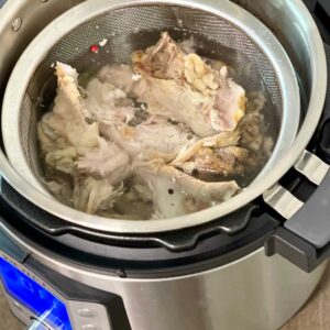 bones in mesh sieve seen from the top inside an Instant Pot Duo Evo Plus - for pressure cooker turkey stock