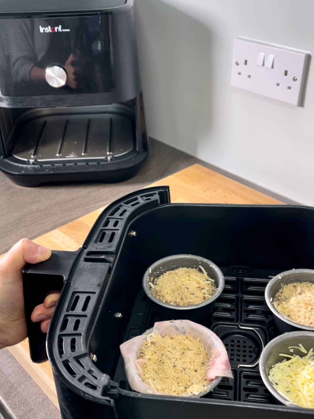 Egg pots placed inside black Instant Vortex air fryer basket