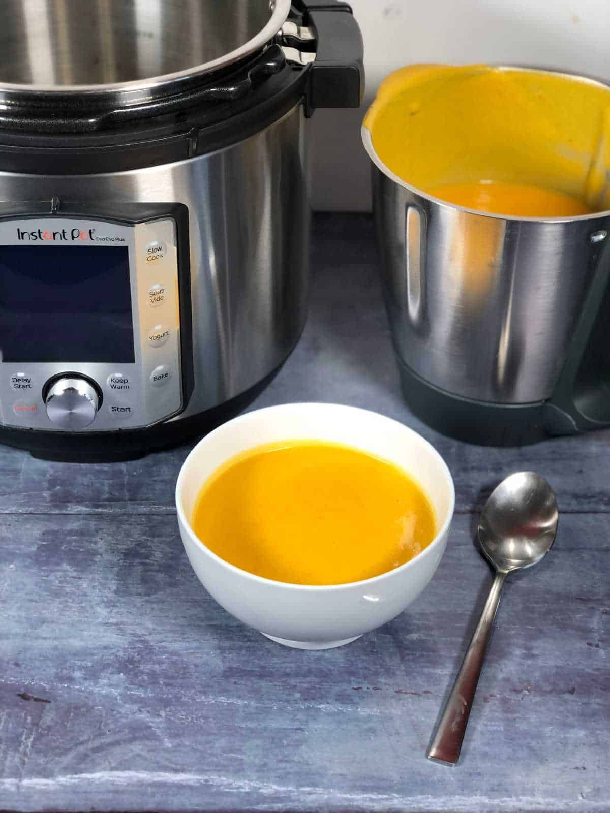 Photo of the butternut squash soup in a white bowl, with an Instant Pot Duo Evo Plus and a Thermomix bowl in the background