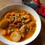 Photo of Instant Pot Chicken and Chorizo Stew seen on a white plate against a wooden surface
