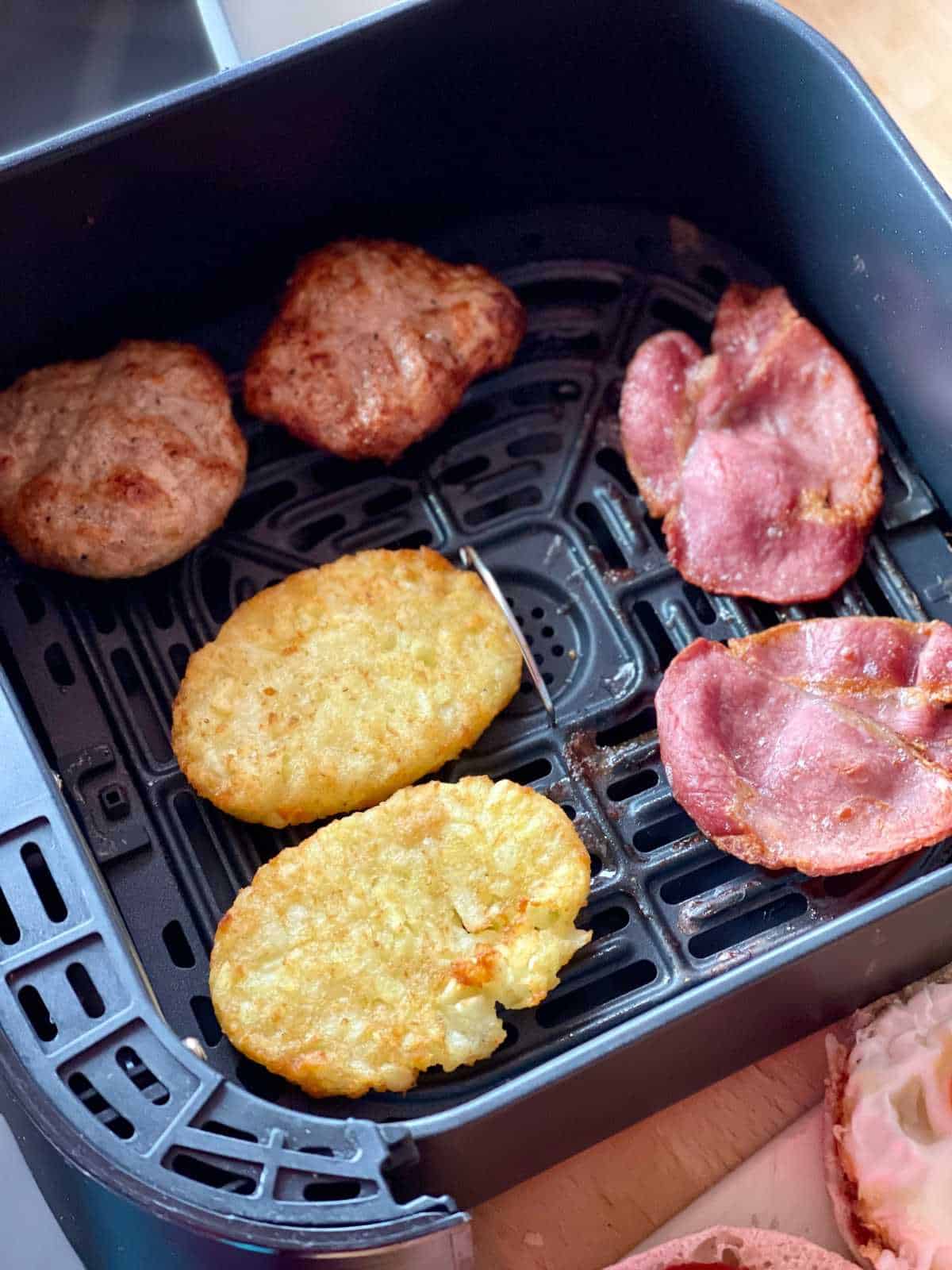 photo of Step air fried ingredients for McMuffins - seen in air fryer basket of Instant Vortex - hash browns, bacon rashers, sausage patties