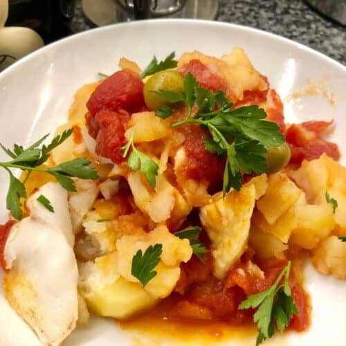 Photo of the pressure cooked fish stew with olives and potatoes served on a white plate