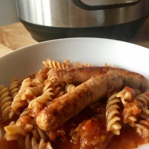 Photo of the sausage pasta served with the fusilli on a white plate with an Instant Pot Duo in the background
