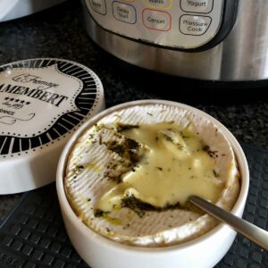 A round camembert cheese wheel pressure cooked melting and ready to dip into