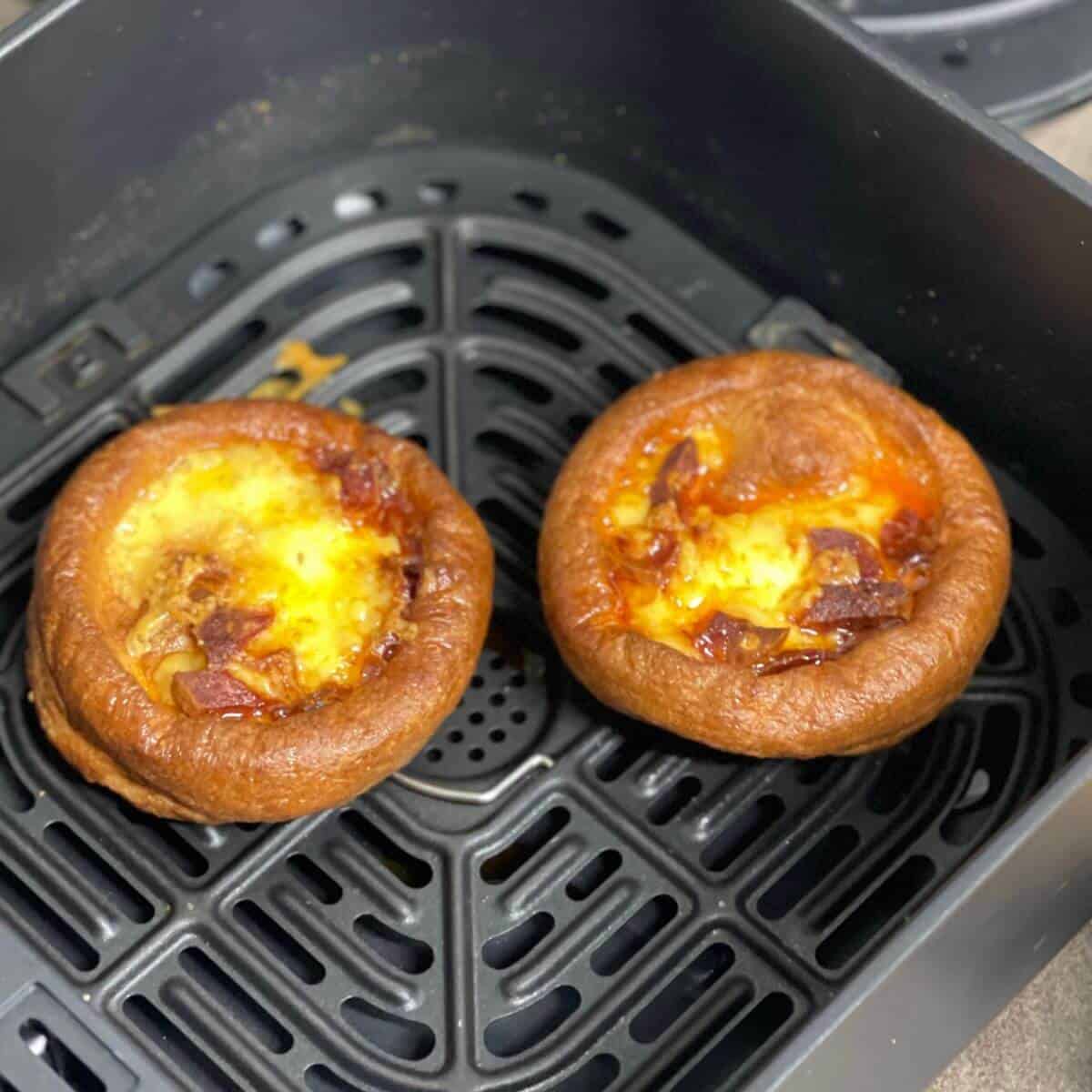 Photo of twwo mini Yorkshire puddings loaded with cheese and chorizo seen from above inside the Instant Vortex air fryer basket