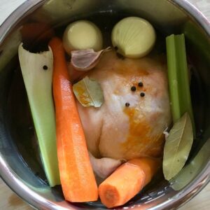 Photo from above of the stainless steel inner pot with the whole chicken and all other ingredients already inside ready to pressure cook
