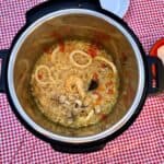 Photo of the pressure cooked Instant Pot seafood rice seen from above inside the Instant Pot, against a red and white gingham background