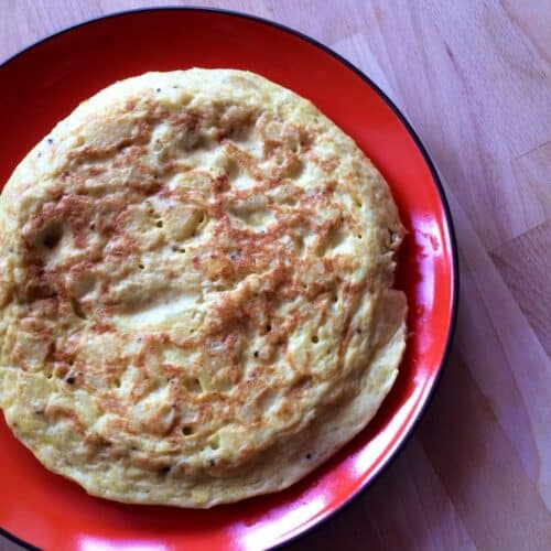 Photo of the tortilla de patatas (Spanish Potato Omelette) seen from above on a round orange plate