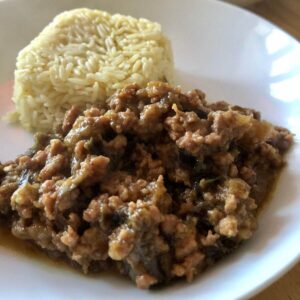 Photo of the pressure cooked Pork and Aubergine served on a white plate with a portion of rice shaped as a square