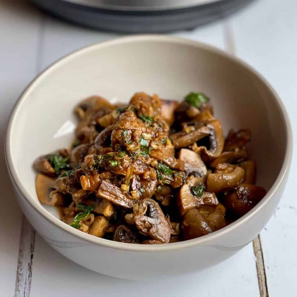 Close-up of the Baharat Mushrooms served in a bowl that's beige on the inside and grey on the outside