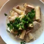 Photo of the delicious Chicken and Pancetta rigatoni seen from above surrounded by sauce on a white plate