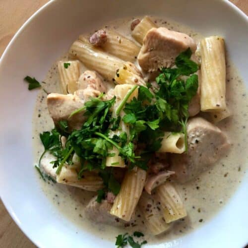 Photo of the delicious Chicken and Pancetta rigatoni seen from above surrounded by sauce on a white plate