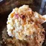 The image shows a large spoonful of pressure cooked Gammon rice with a delicious cheesy top being lifted away from the rest of the pot of rice