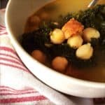 A photo of the delicious soup served in a white bowl with a tea towel underneath, you can clearly see the kale , chorizo and chickpeas