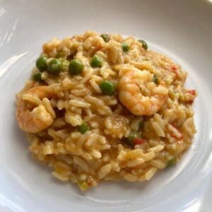 Photo of the Instant Pot Prawn, Trout and Pea Risotto with the rice, peas and a couple of king prawns ready to eat served on a white plate