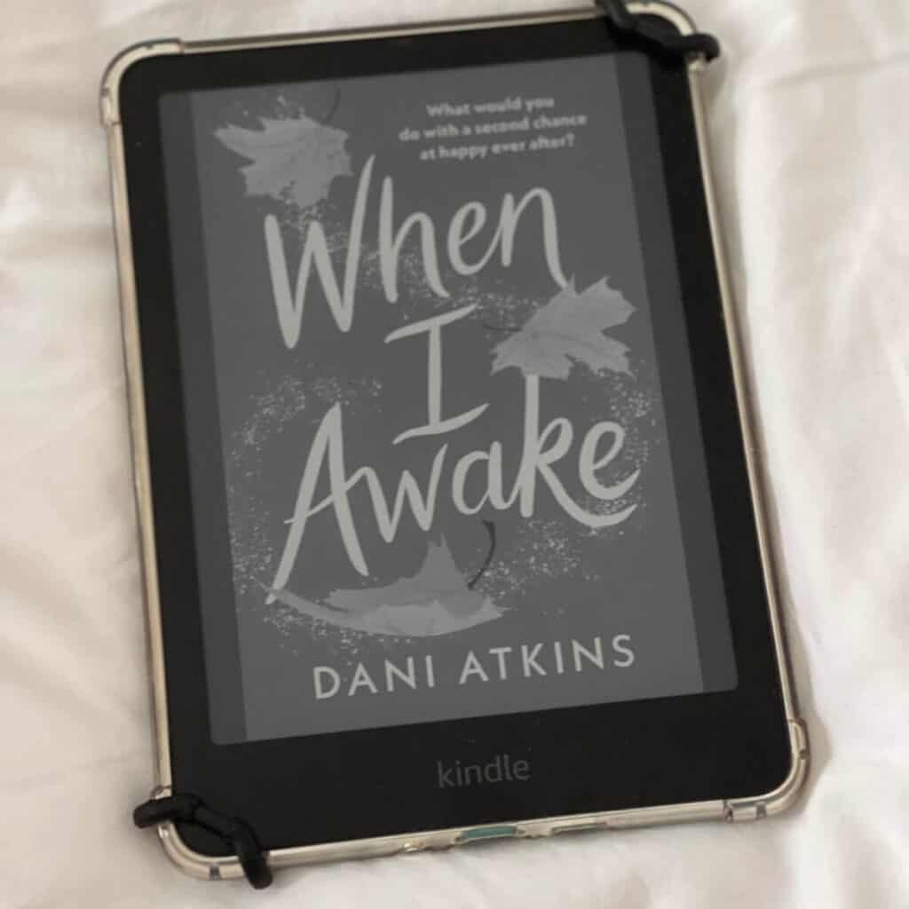 Photo of a kindle paperwhite, it's showing the book cover for the book When I awake by Dani Atkins