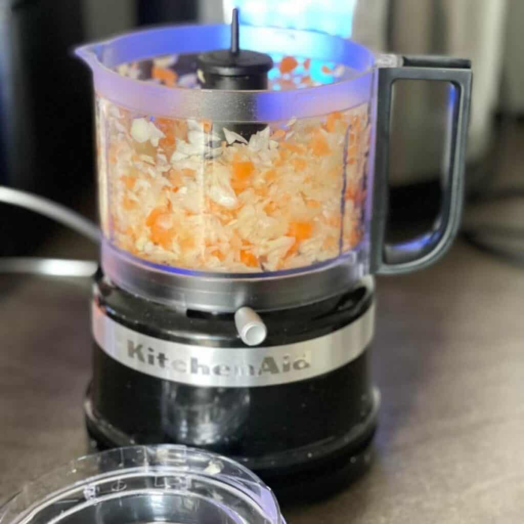 Photo of a kitchenaid mini chopper with chopped onion and carrot inside