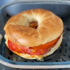 Close-up of the bagel inside the glass container of the Ninja Crispi showing the chorizo and melted cheese
