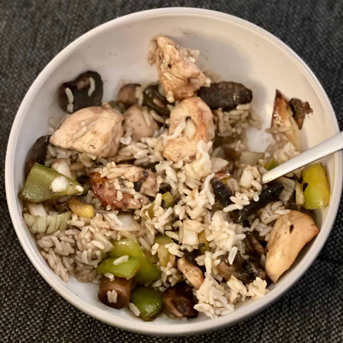 Chicken in Oyster Sauce mixed with brown rice in a white ceramic bowl