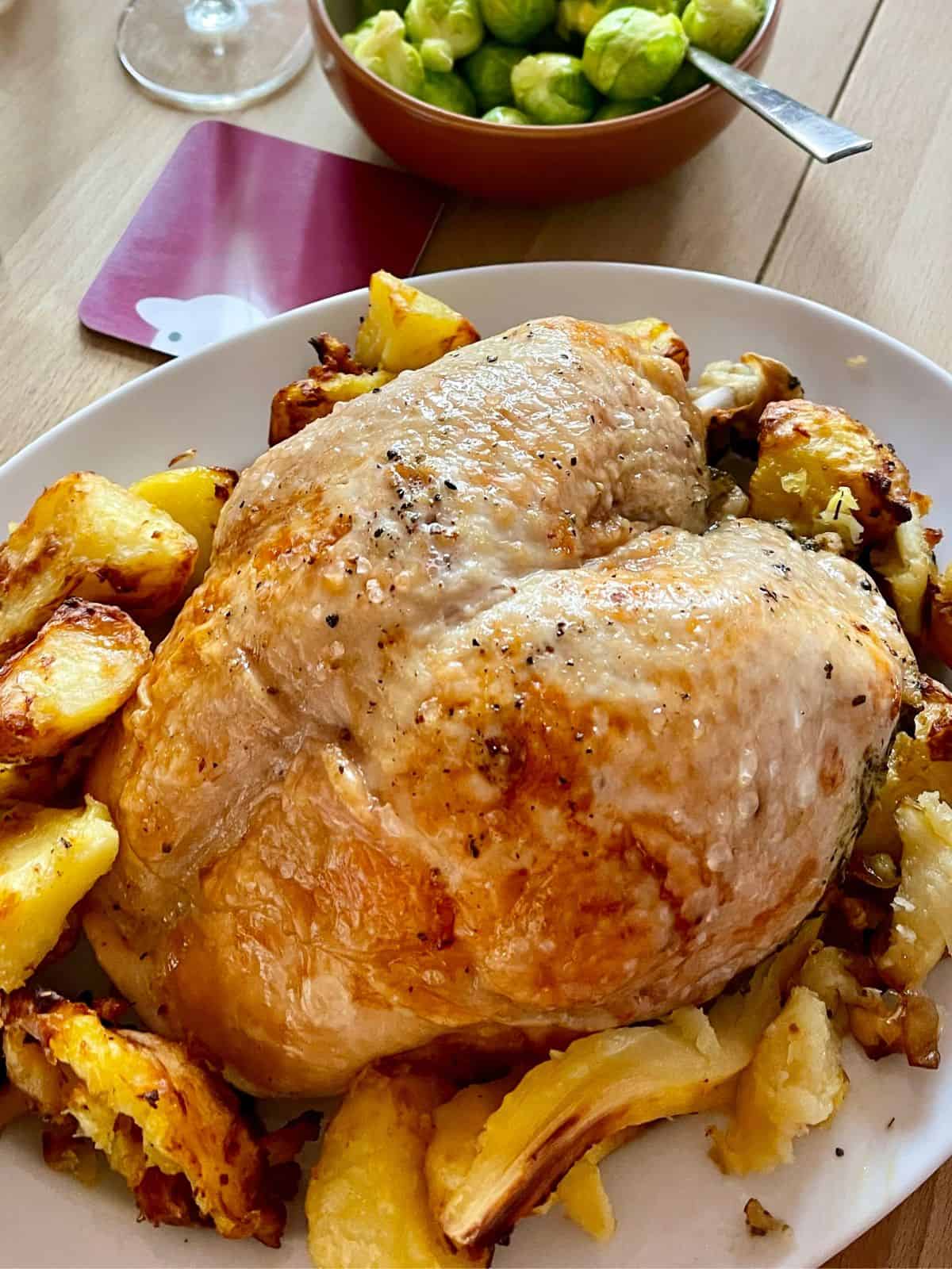 Turkey crown without bacon served on a white oval plate surrounded by crispy roast potatoes and parsnips