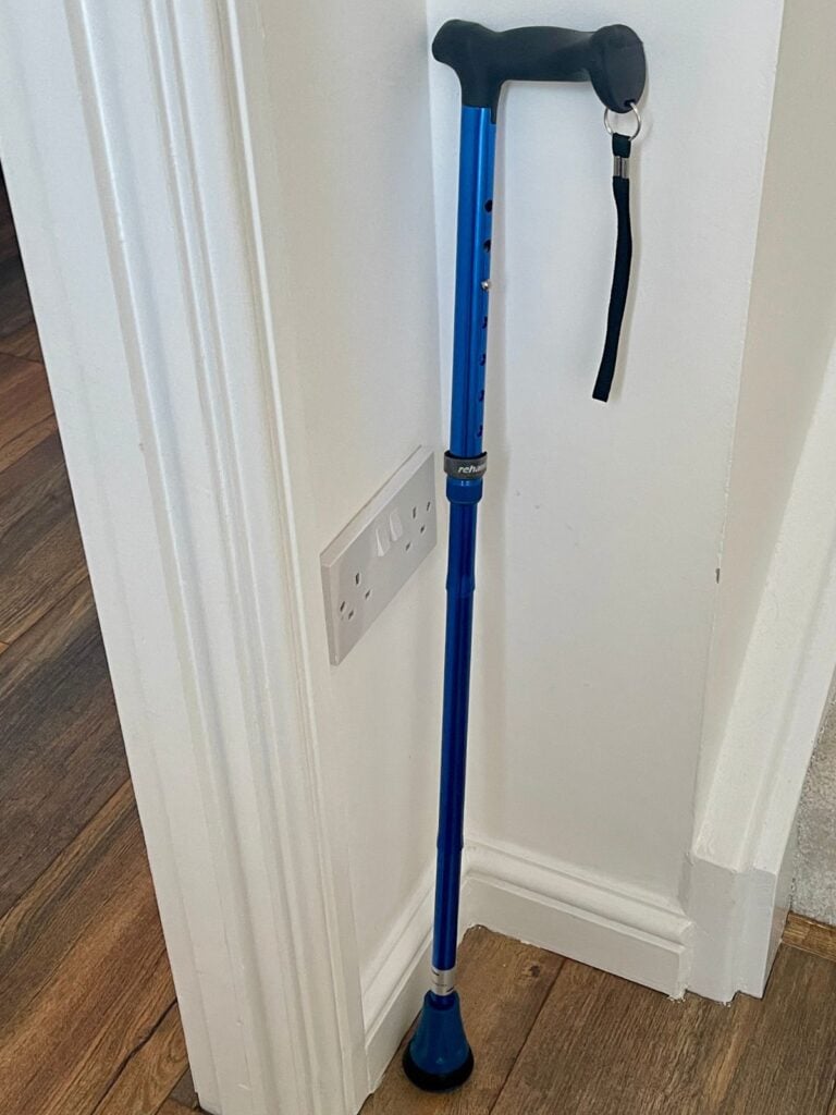 A metallic blue walking cane leaning against a white corner