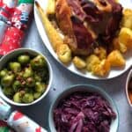 Pressure cooked Turkey crown, roast potatoes and parsnips served in an white dish with a bowl with Brussels sprouts and another with red cabbage