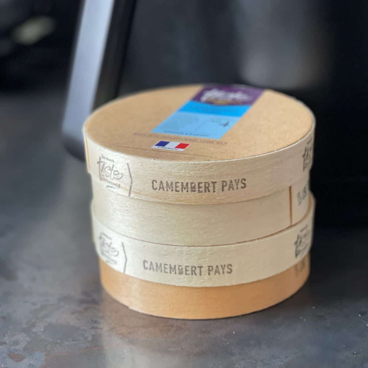 Two Sainsbury's Taste the Difference Camembert de Pays boxes in front of an air fryer