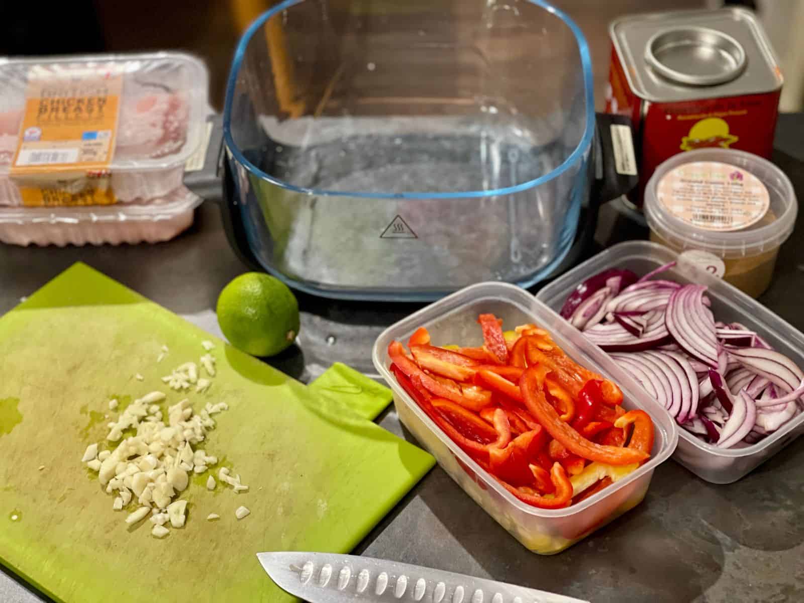 The ingredients for the fajitas laid out around the large glass base of the Ninja Crispi