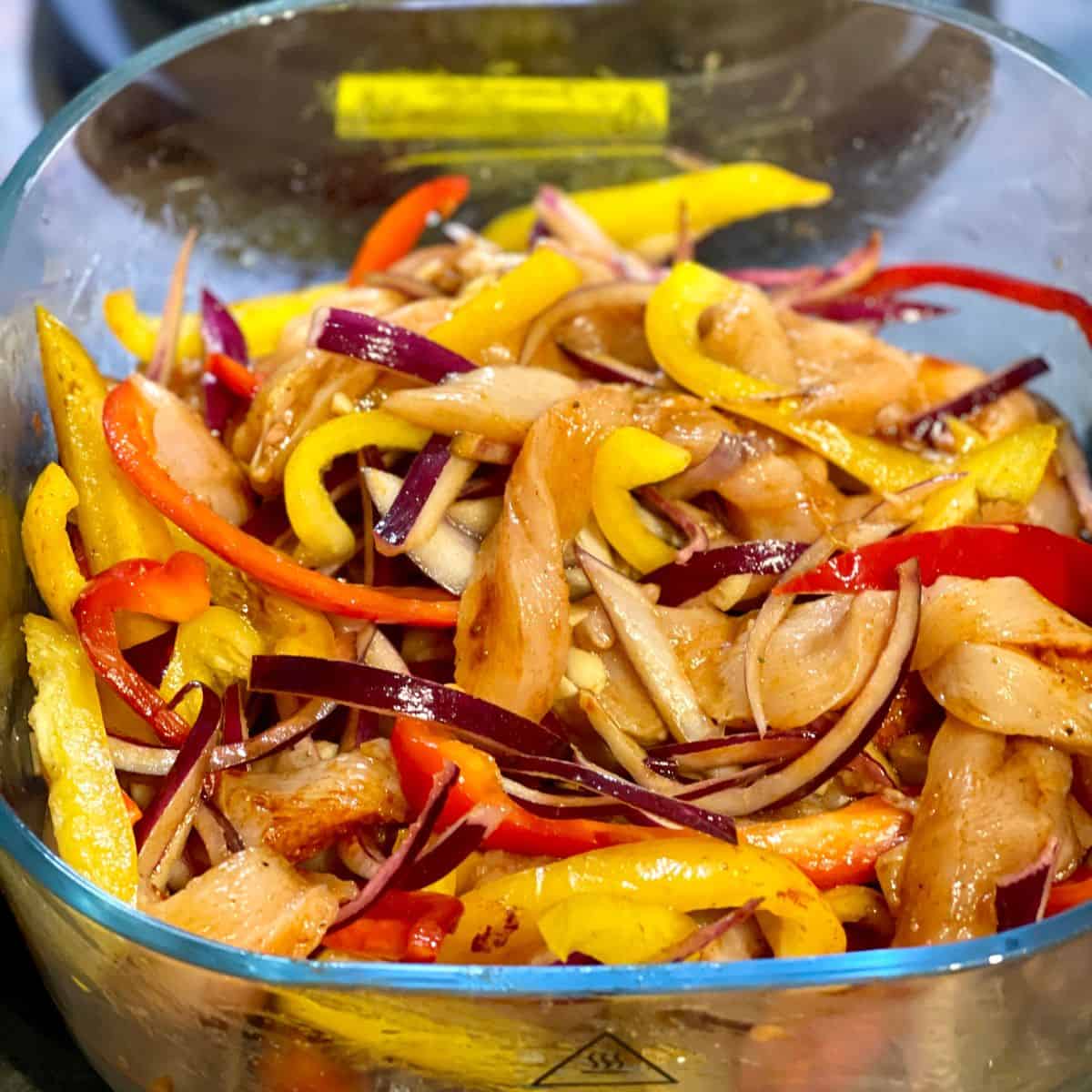 The ingredients for the chicken fajitas mixed well inside the glass base of the Ninja Crispi, the air fryer lid is in the background
